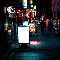 ネオンサインが光る飲み屋の看板と提灯が並ぶ裏路地の写真