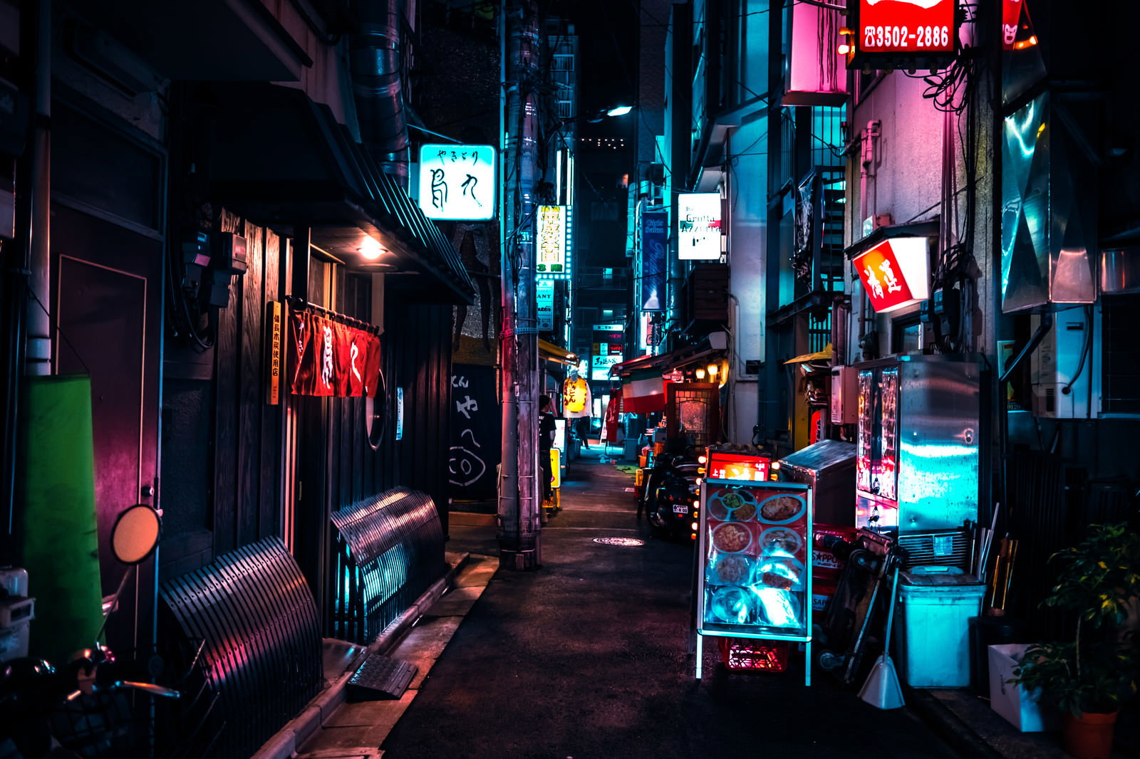 夜の裏通りでネオンサインが光る飲み屋街の風景