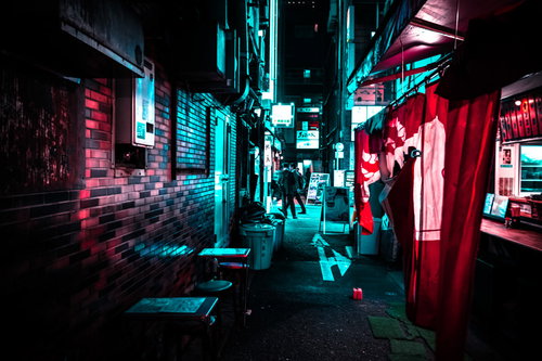 ネオンサインが煌めく裏路地から見える行き交うサラリーマン