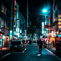 ネオンが光る裏通りの飲み屋を行き交う人々の写真