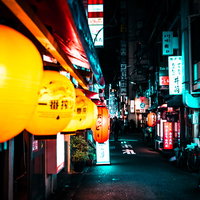 居酒屋の軒下に並ぶちょうちんと飲み屋街の夜景の写真