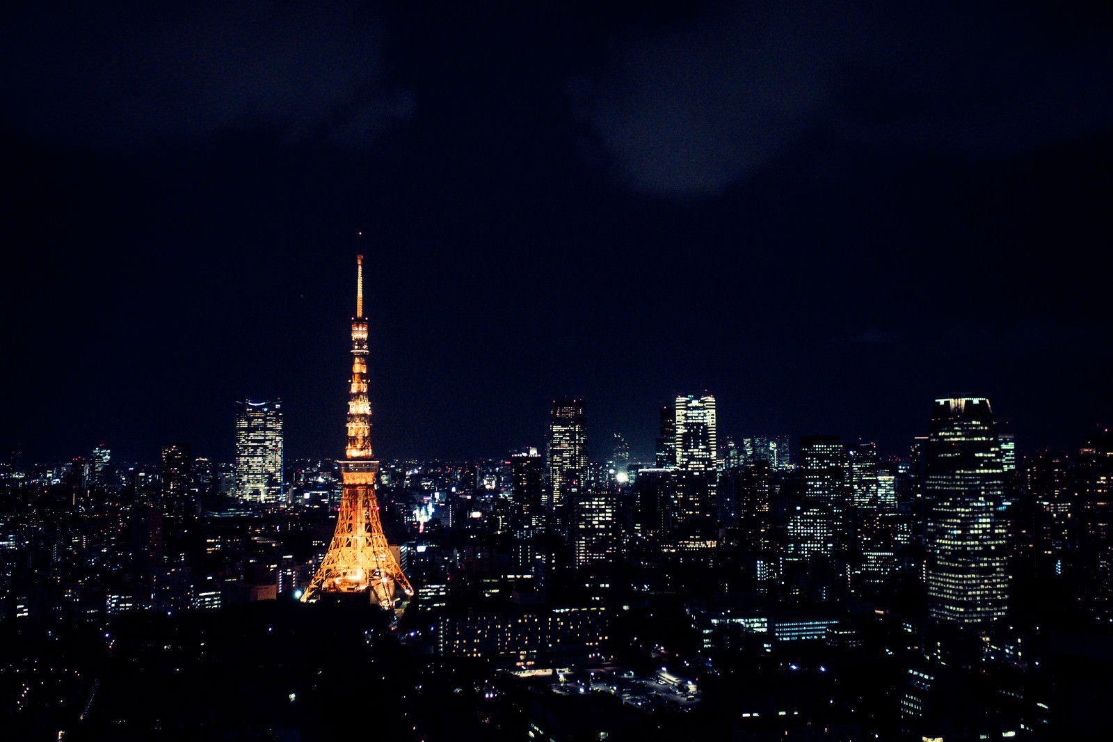 夜間にオレンジ色にライトアップされた東京タワーと周囲の高層ビル群の夜景