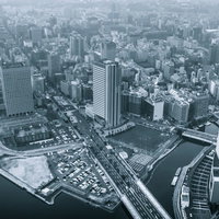 高い位置から霞がかった曇りの日に撮影した水辺沿いの高層ビルの都市風景の写真