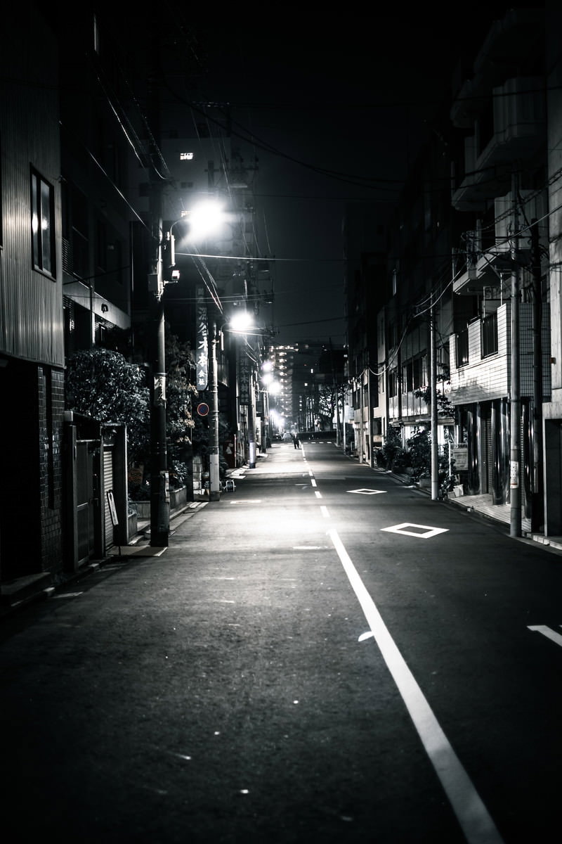 夜間に街灯で照らされた住宅街の狭い道路