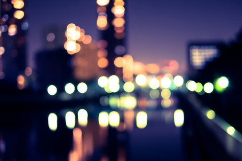 街灯とビルの窓灯がボケた夜景、紫紺の夜空に映える都市風景