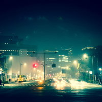 信号機と街灯がある夜の都市の大通りを走る車の光跡の写真