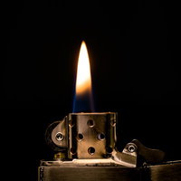 金色装飾のオイルライターから立ち上がる青と黄色の炎の写真