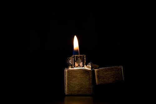 金色のオイルライターから立ち上る白と黄色の炎