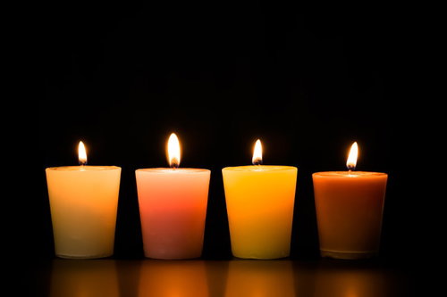 灯りをともしたキャンドルの並び、クリーム色からダークオレンジまで4色