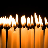 誕生日を彩る複数のろうそくの炎が灯る黒背景の写真