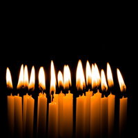 火がついた複数の和ろうそくが黒い背景に並ぶの写真