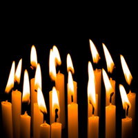 黒い背景に立てられたろうそくの炎が揺らぐ追悼シーンの写真