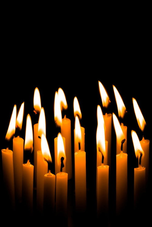 黒い背景に立てられたろうそくの炎が揺らぐ追悼シーン