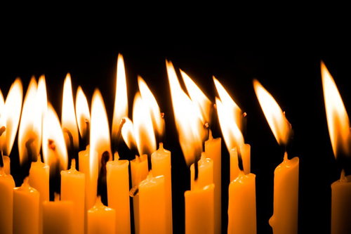 黒い背景に並ぶ複数のろうそくの炎が揺らぐ