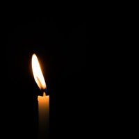 風で揺らめく蝋燭の炎 - 黒背景に浮かぶオレンジ色の光の写真