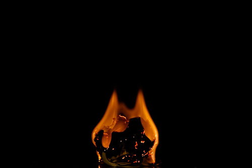 黒背景に映える赤とオレンジの炎が燃える紙くず