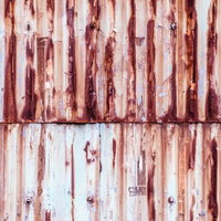 赤茶色に錆が目立つ塗装剥がれのトタンの壁の写真
