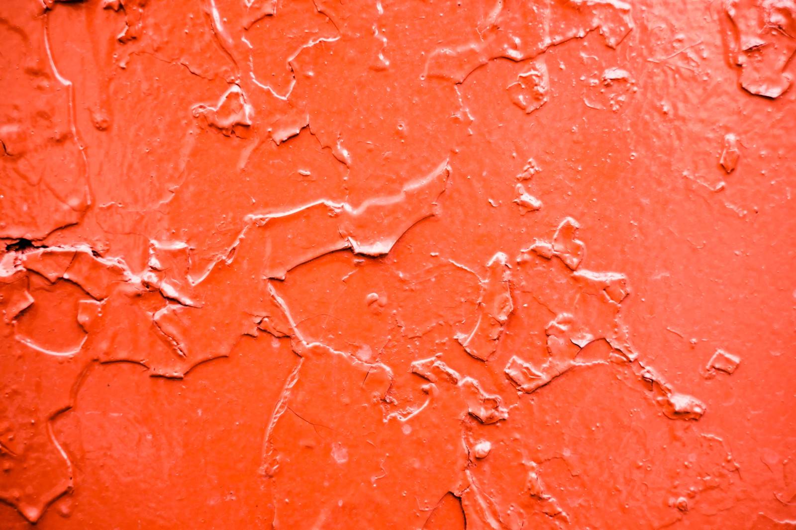 赤い塗装が剥がれ落ちて劣化した壁面のテクスチャー