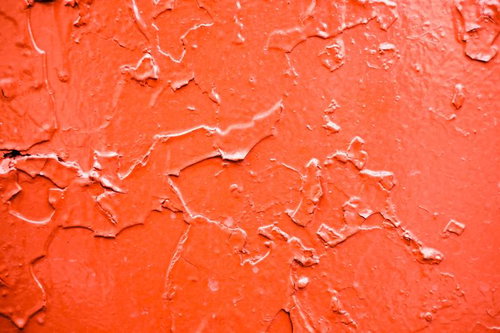 赤い塗装が剥がれ落ちた壁面のテクスチャー