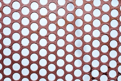 赤茶色の板に規則的に空いたドット穴のテクスチャー