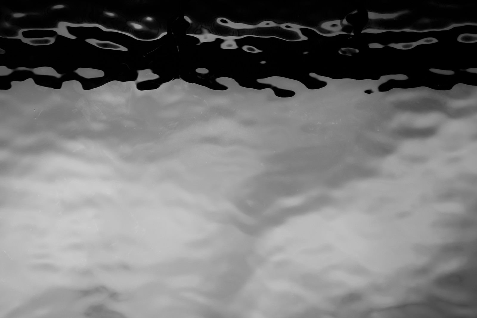 水面を真上から撮ったモノクロ写真に映る人影