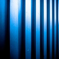 凹凸のあるメタルの壁に映る青い光と影の写真