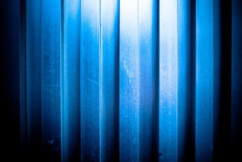 凹凸のあるアルミの壁に入った青いストライプテクスチャ