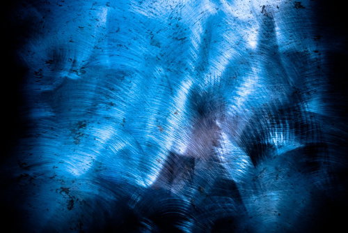 青い光が反射する金属の擦り後が残る板のテクスチャー