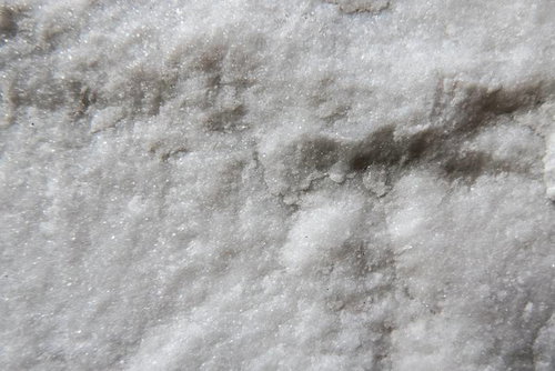ざらついた結晶の粗い表面。白とグレーの鉱物テクスチャ