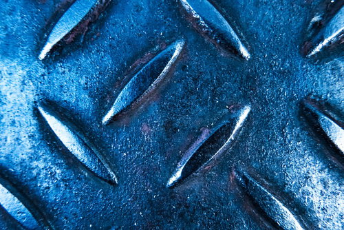 青白い金属製の足場板に施された滑り止め加工