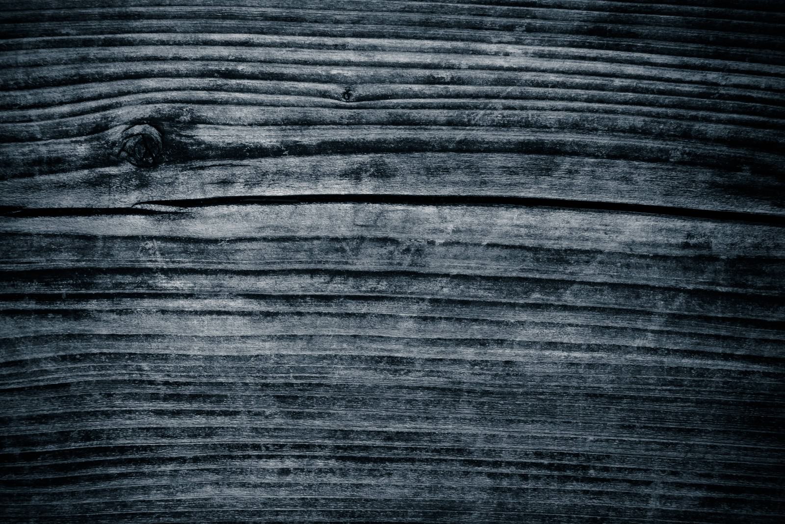 深い色合いの古い木の板に横方向の木目が入った表面