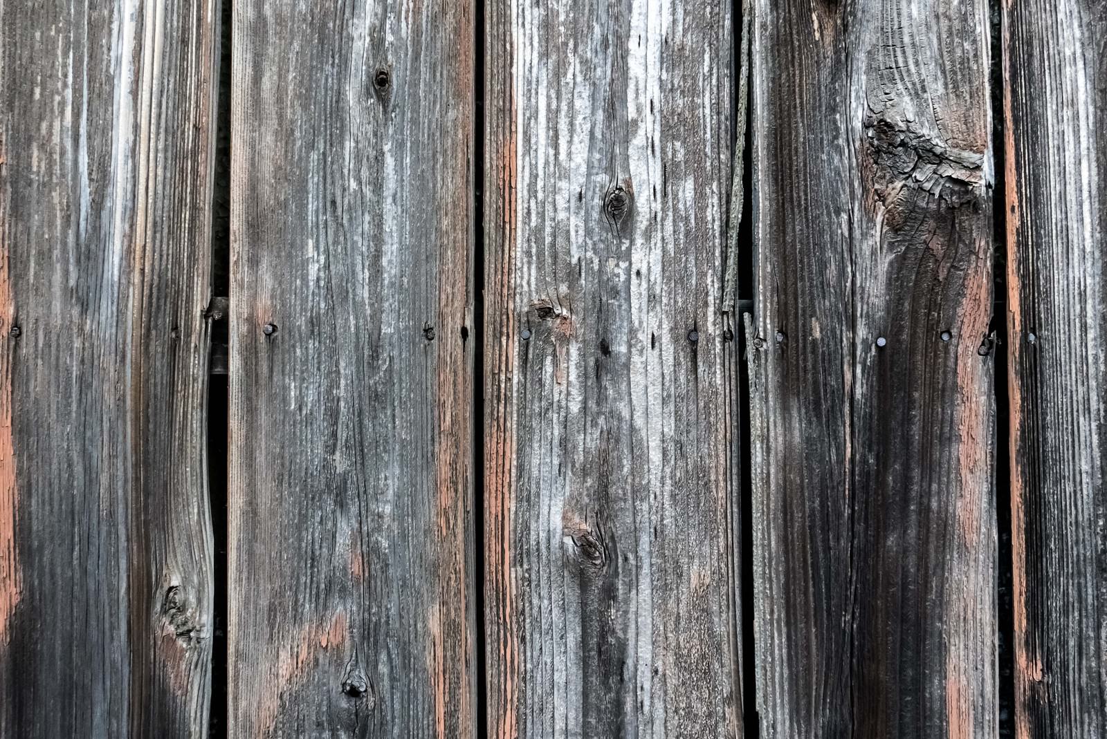 縦に並んだ古い木の板に錆びた釘が打ち込まれた柵のテクスチャ
