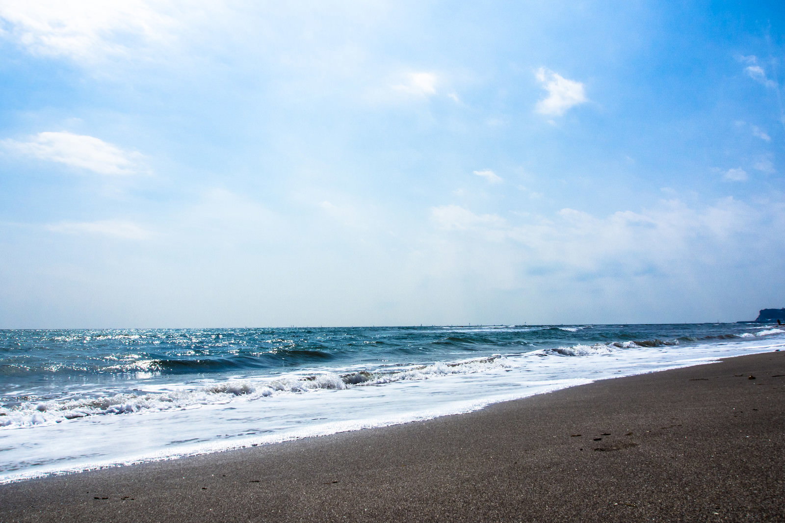 晴れた日に波が打ち寄せるビーチの海岸風景