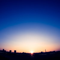 日の出と街並みのシルエット、水面に映る朝焼けの風景の写真