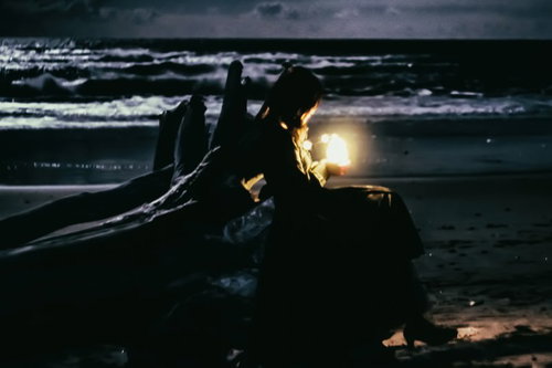 夜の海岸で流木の隙間から漏れる灯り