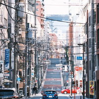 右へ左へ張り巡る電線と車道の都市風景の写真