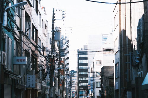 住宅地の建物間に縦横に伸びる電線と電柱の日常風景