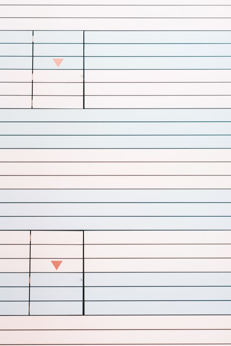 パステルピンクとブルーのストライプ壁に白い扉と緑の矢印がある非常口