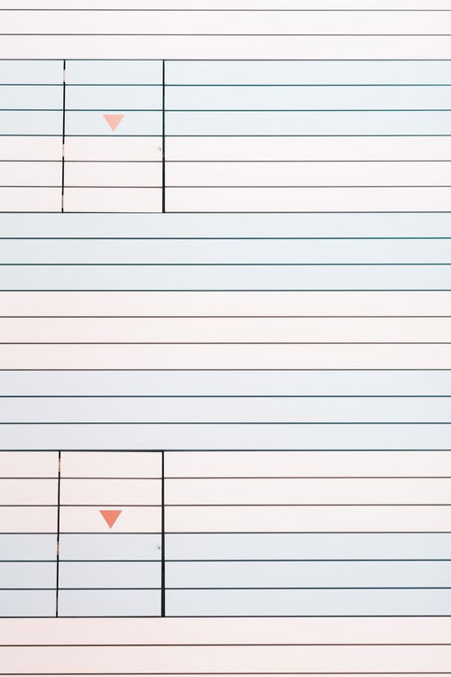 パステルカラーの壁に設置された白い非常口の扉と緑色の矢印