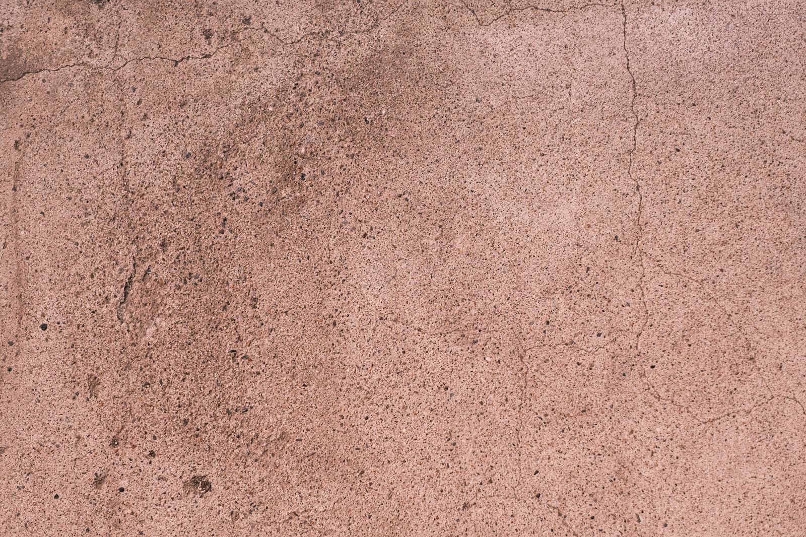 薄いピンク色のコンクリート壁に細かなひび割れが入った質感