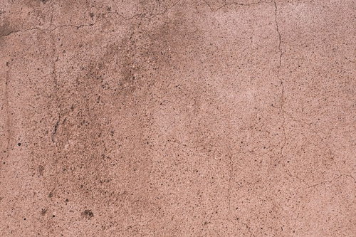 うっすらとピンク色のコンクリート壁に細かく入るヒビとクラック