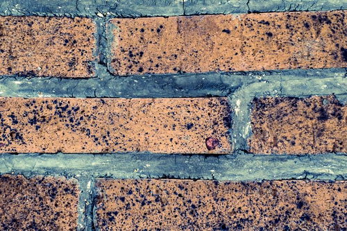 経年劣化した茶色いレンガタイルと青灰色モルタル目地の外壁