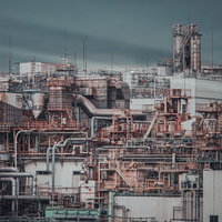 曇り空の下に立ち並ぶ工場のプラント設備と配管システムの写真