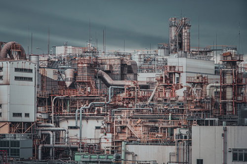 曇り空の下に立ち並ぶ工場のプラント設備と配管システム