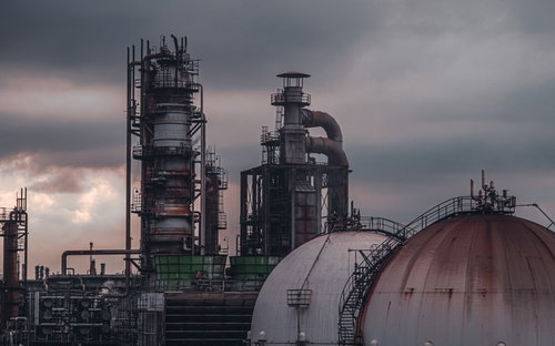 曇り空に佇む工場とプラント施設の大型タンクと煙突