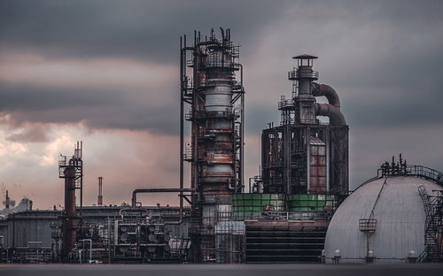 工業地帯に立ち並ぶ複数の煙突と曇り空の風景