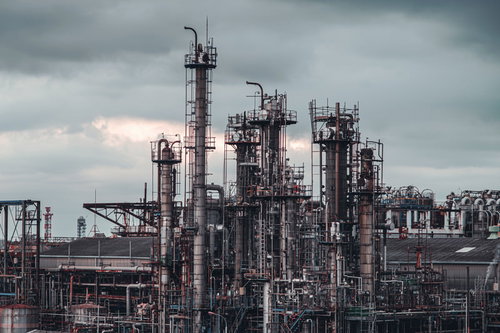 曇り空に立ち並ぶ工場の煙突とパイプライン