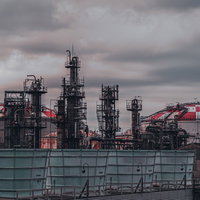 曇り空と工場用タンク、煙突が立つプラントの写真