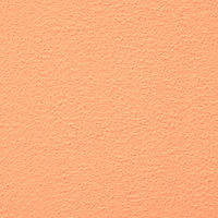 淡いオレンジ色に塗装した外壁のテクスチャーの写真