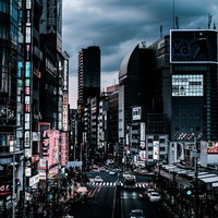 夕暮れ過ぎの新宿大ガード西の交差点前、ネオンが灯る繁華街の写真